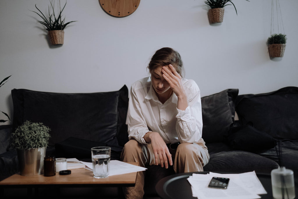 Woman holding her aching head while sitting on a sofa.