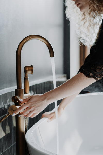 Woman tapping up a bath at home.