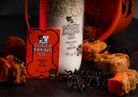 Doggy Baking Co Carrot Cake bottle with treats surrounding and toy spiders on top - Halloween bakes perfect for a party