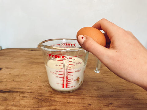 Cracking eggs into jug of milk