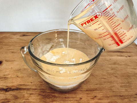 Pouring milk and eggs into mixing bowl