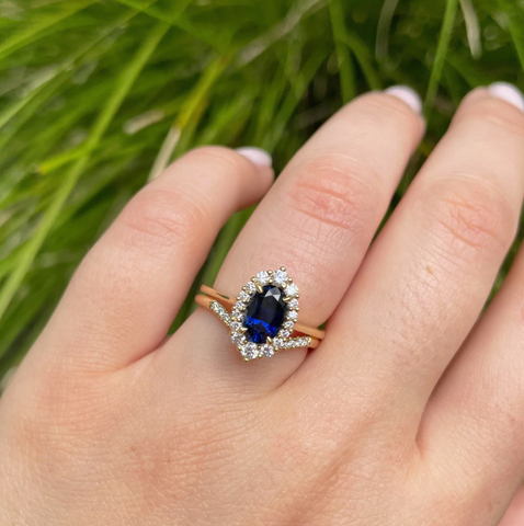 blue-sapphire-engagement-ring-on-hand-in-front-of-plant-background