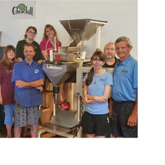 Churchill Coffee Company employees standing in front of coffee bag filling machine