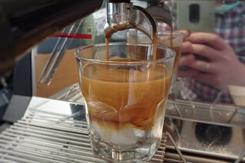 Ein Glas mit Eiswürfeln, Tonic und Espresso