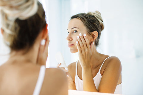 Women Looking In Mirror Touching Cheek