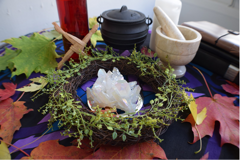 image of an altar with a wreath, crystal, brigid's cross, cauldron, morter and pestel, etc.