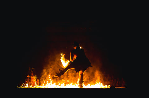 Image of a man dancing silhouetted against a fire