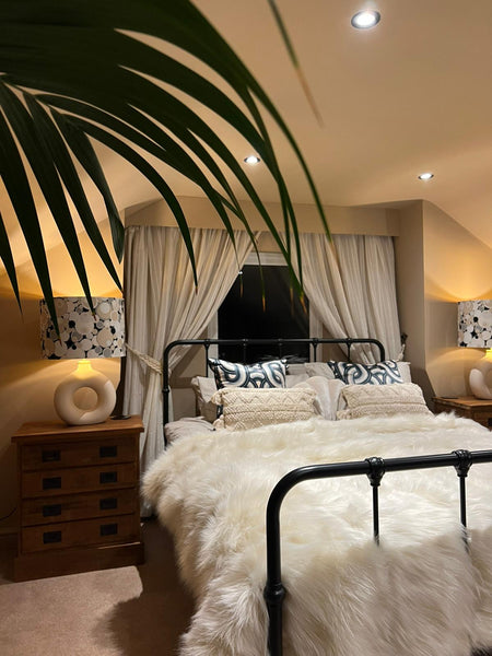 Attic bedroom with neutral tones and cushions from The Curious Department