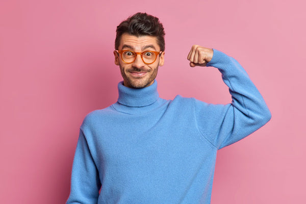 Man making the "I'm strong" motion with his arm, In front of pink background