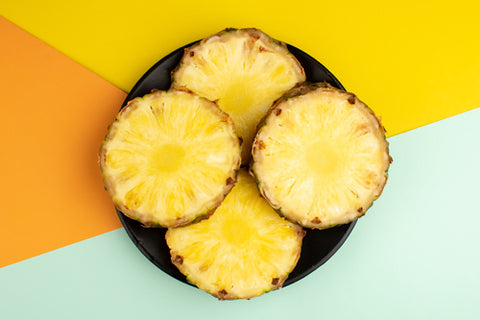 A Plate of pineapple slices on a blue, yellow, and orange background