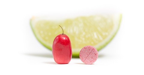 miracle fruit tablet to the right of fresh miracle berry with lime wedge behind