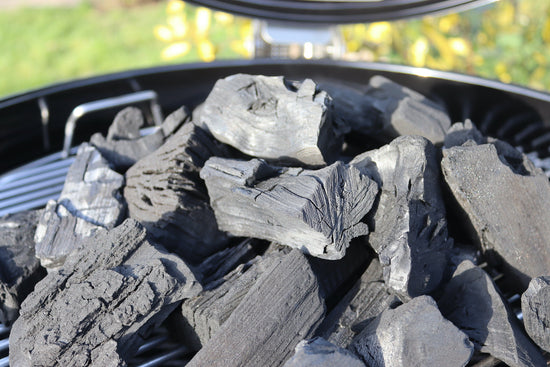 A pile of un-lit lumpwood charcoal on a BBQ