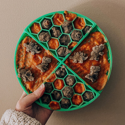 Green lick mat with dinosaur shaped food on it