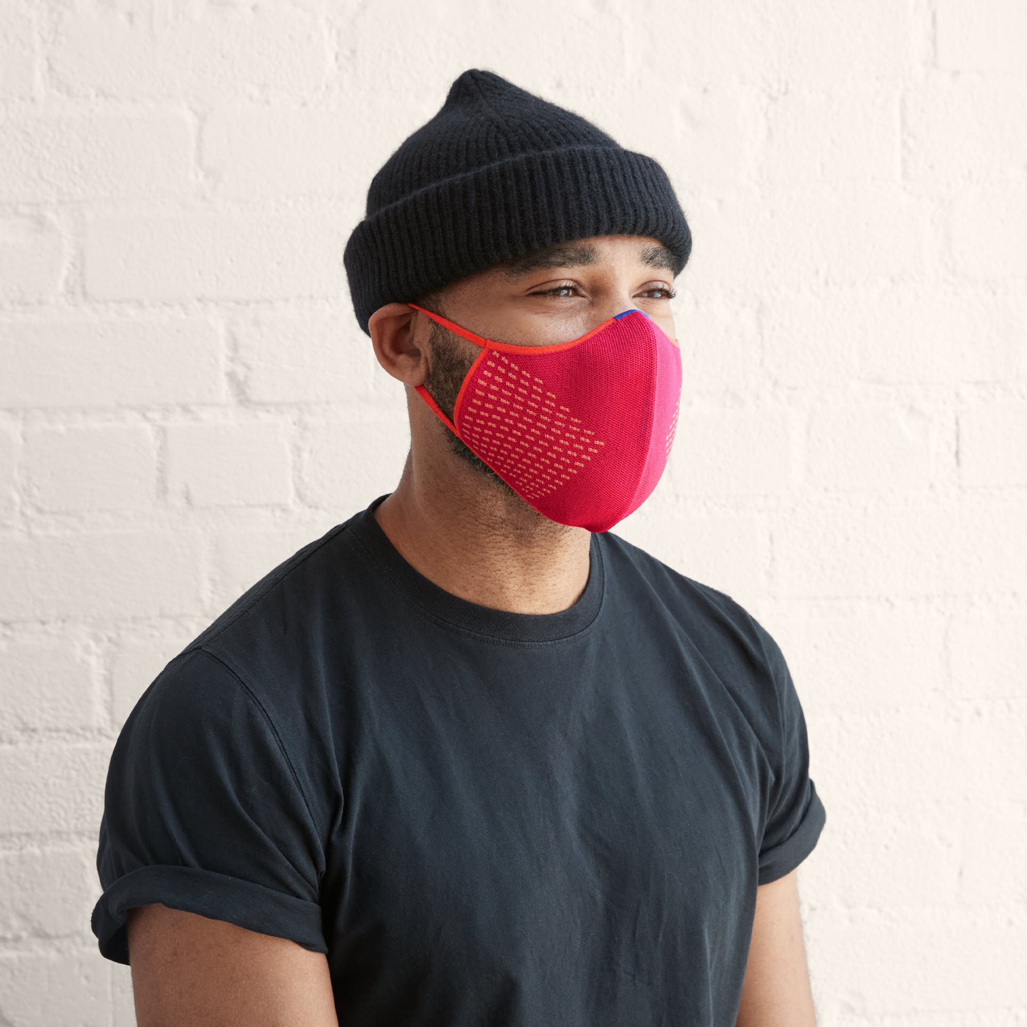 Man shown wearing a bright pink mask with light orange stitching details on the side. 