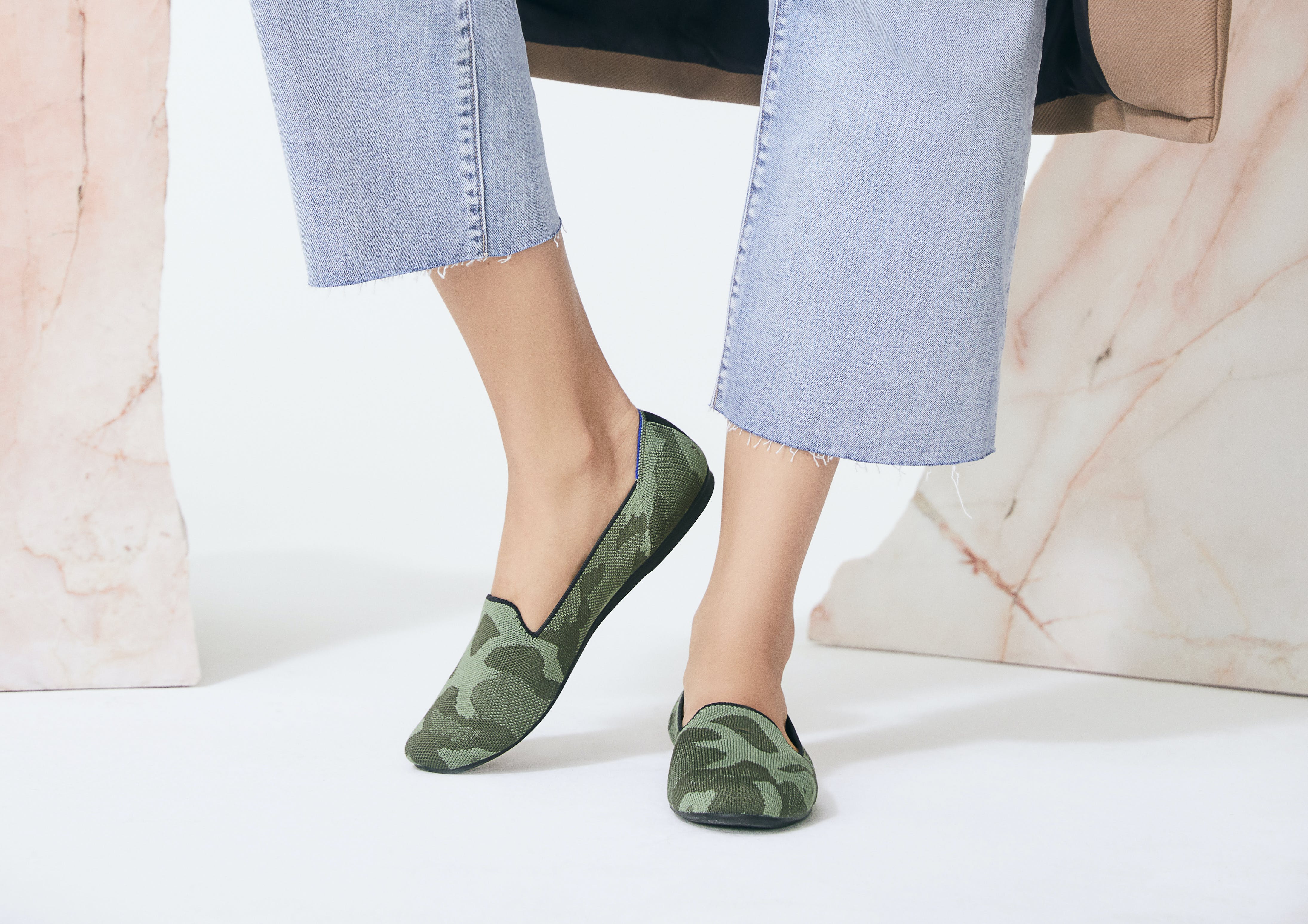 The Loafer in Olive Camo shown on a model's feet, against a cream and marble background. 