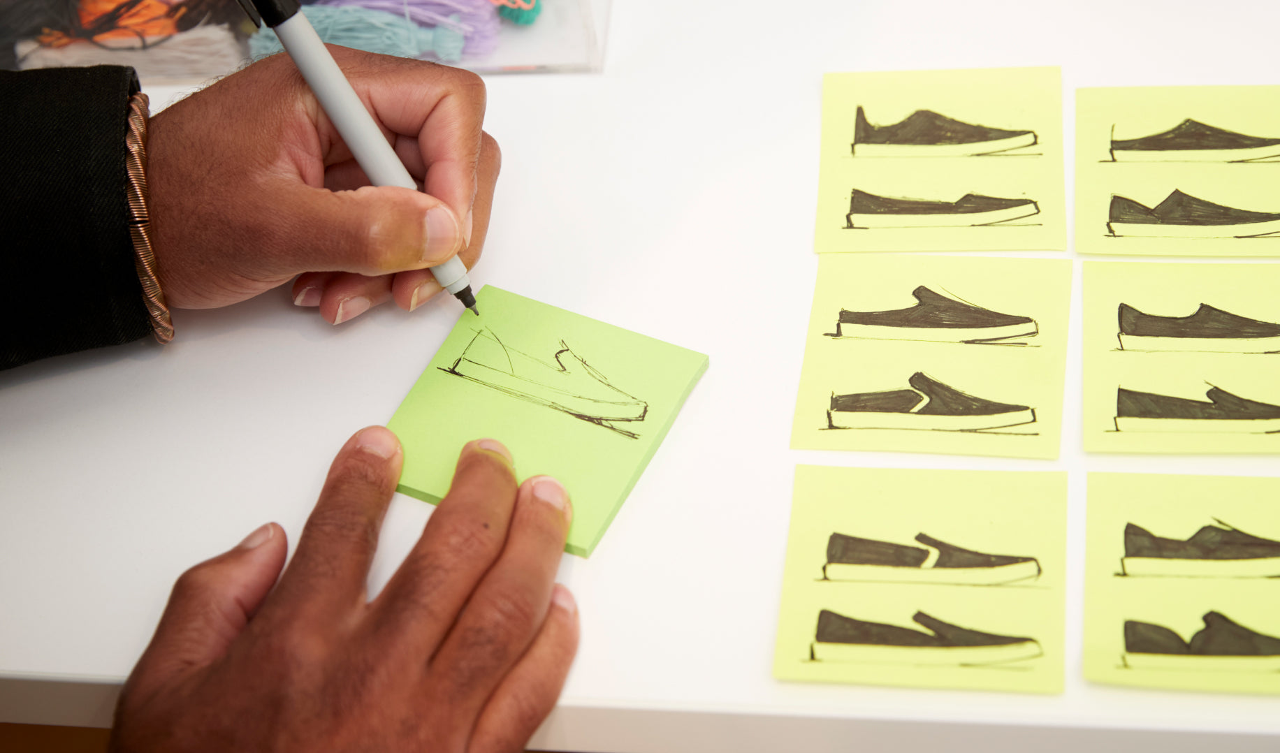 Close up of Lavion sketching designs of The Sneaker on post-it notes. 