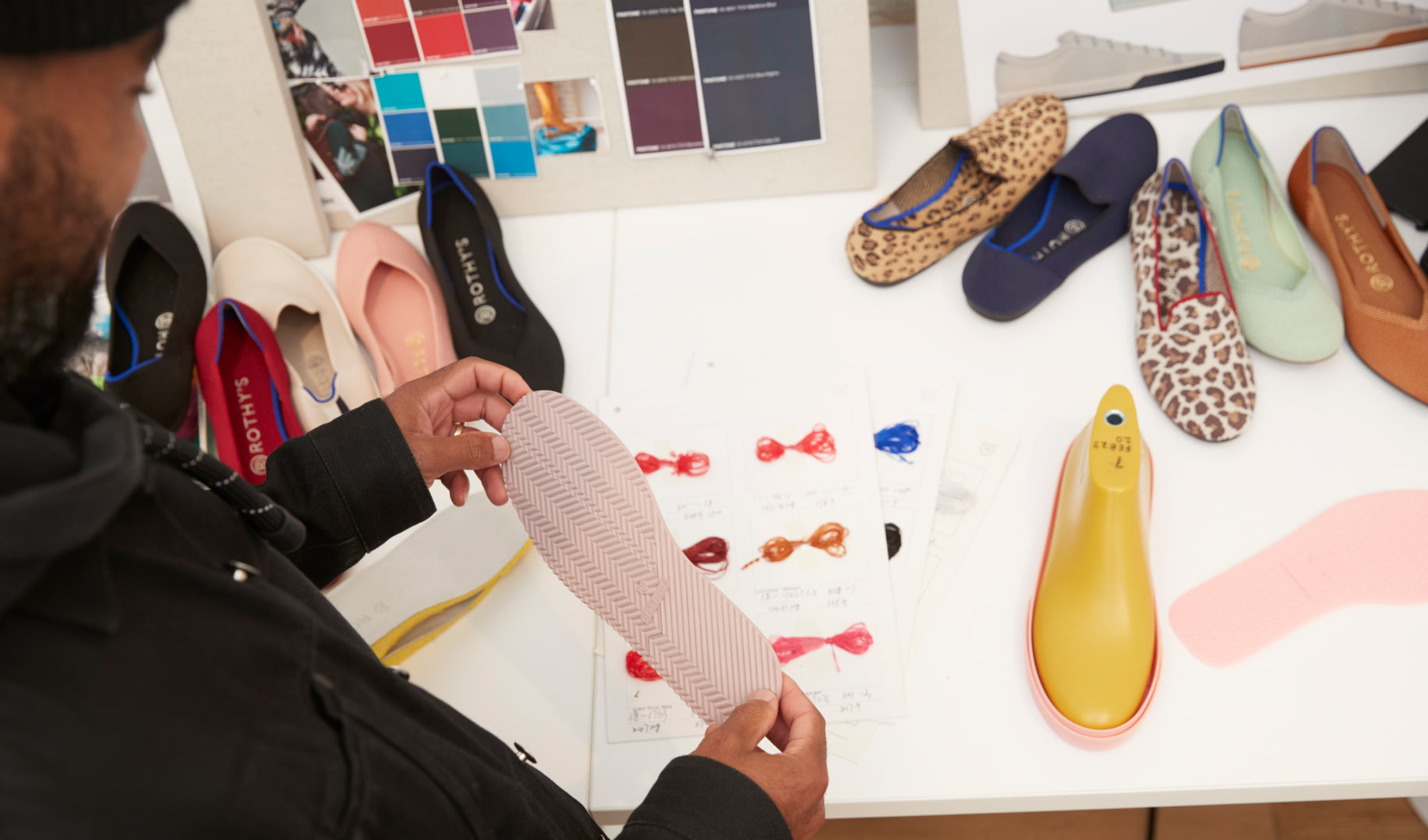 Lavion holding a light pink shoe outsole in front of a table with shoes and design materials.