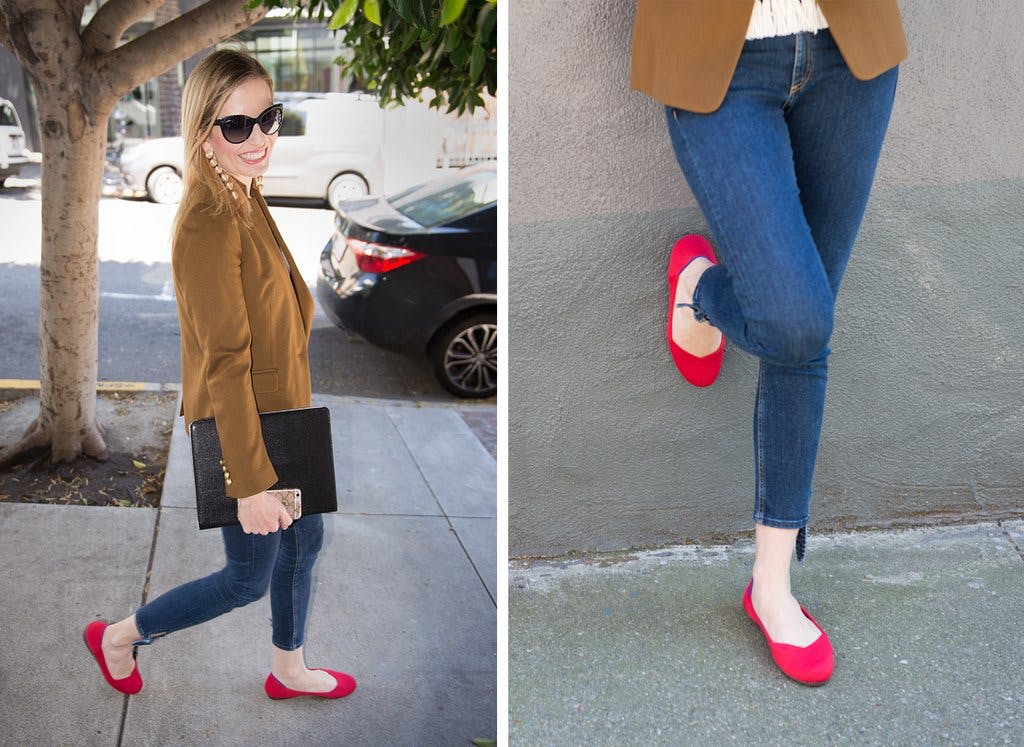 Woman walking on the sidewalk and leaning against a building wall in a pair of red Rothy's flats. 