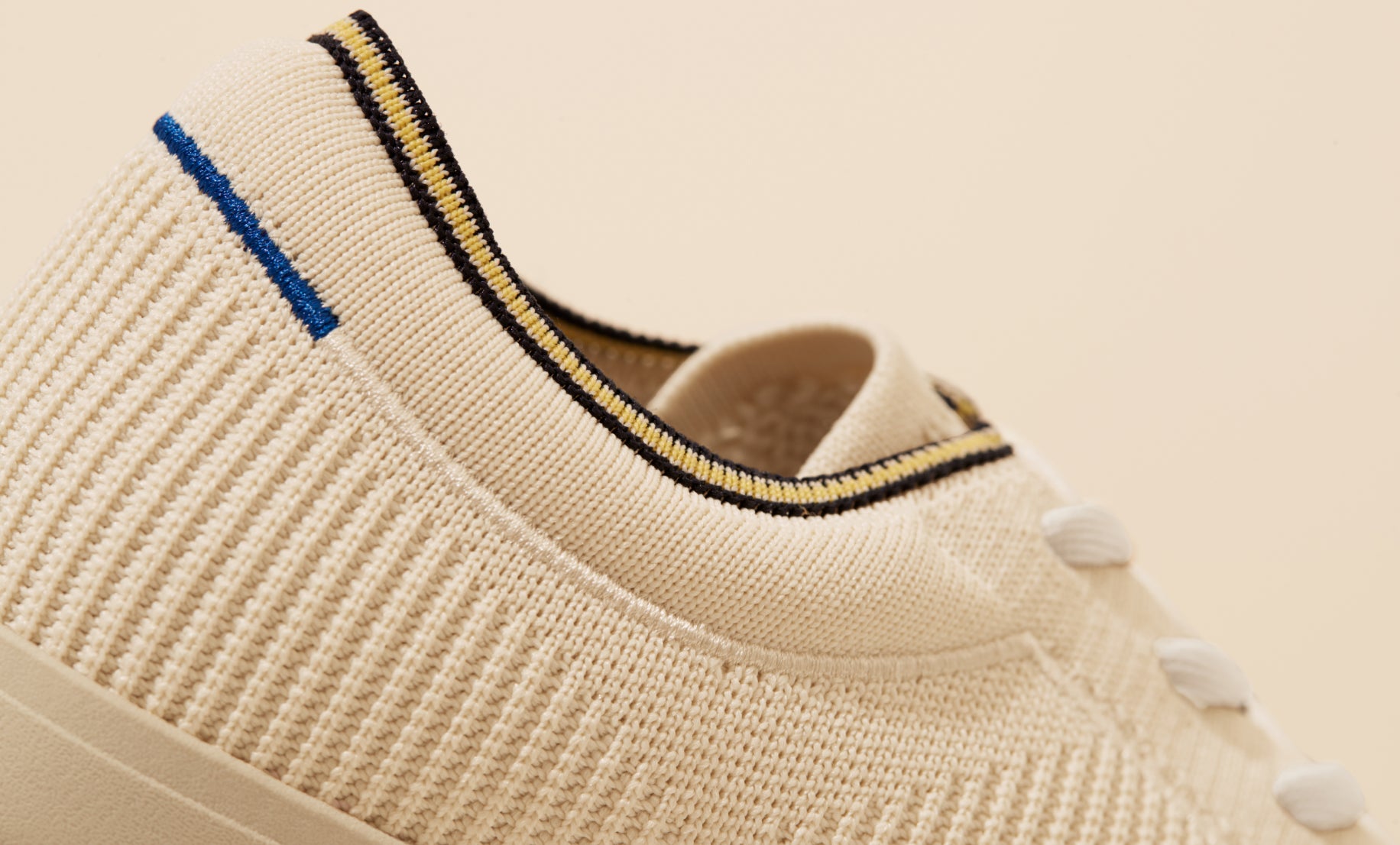 Close up of the plush ankle collar of The Lace Up in Vanilla, showing the navy and yellow striped ankle piping detail. 