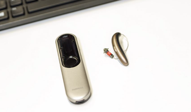 A Phonak slim hearing aid beside the Phonak remote control hearing aid accessory.
