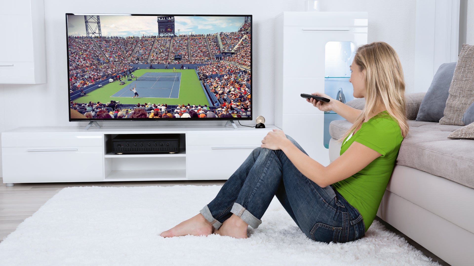 A person watching TV using a hearing aid TV connector.