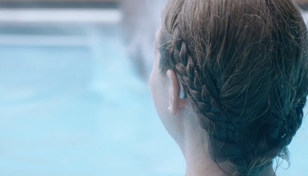 A person in a swimming pool wearing a hearing aid.