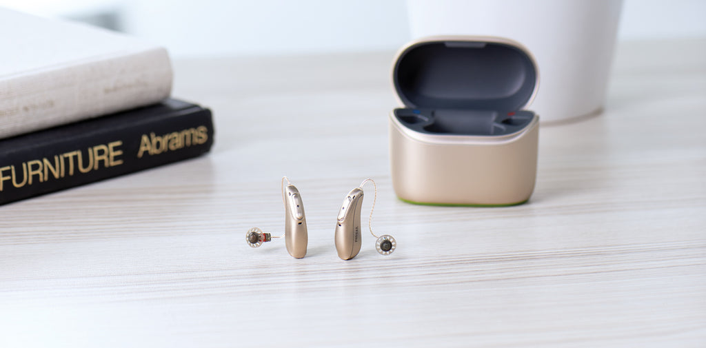 A Phonak Lumity L90 rechargeable hearing aid beside it's hearing aid charger.