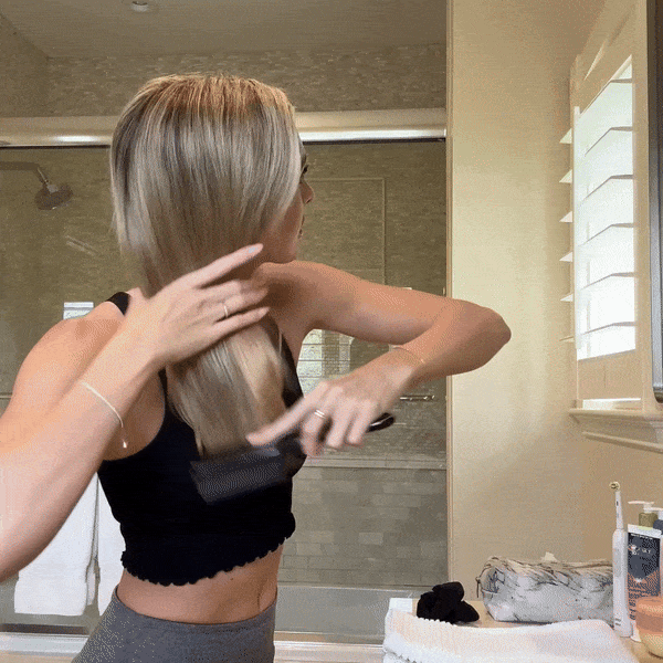 Woman spraying a product into her mouth, smiling.