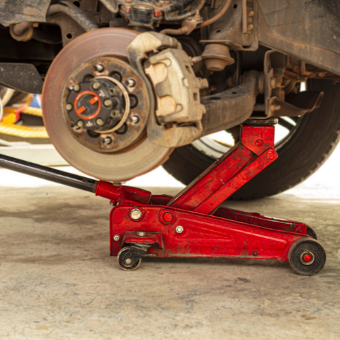 Car Brake Disc on. Car on trolley lifted. Red trolley. Rust on frame