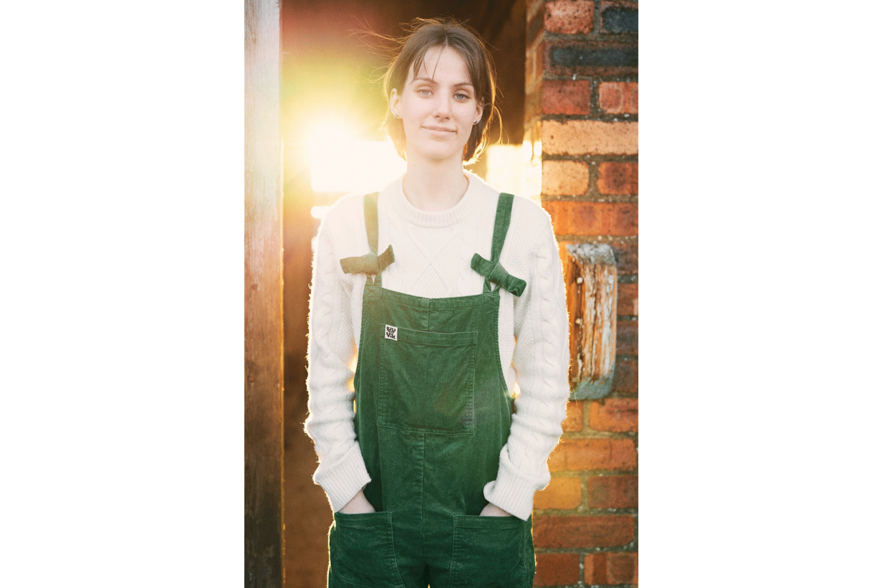 Anna Kingston standing in front of a doorway in a pair of green dungarees