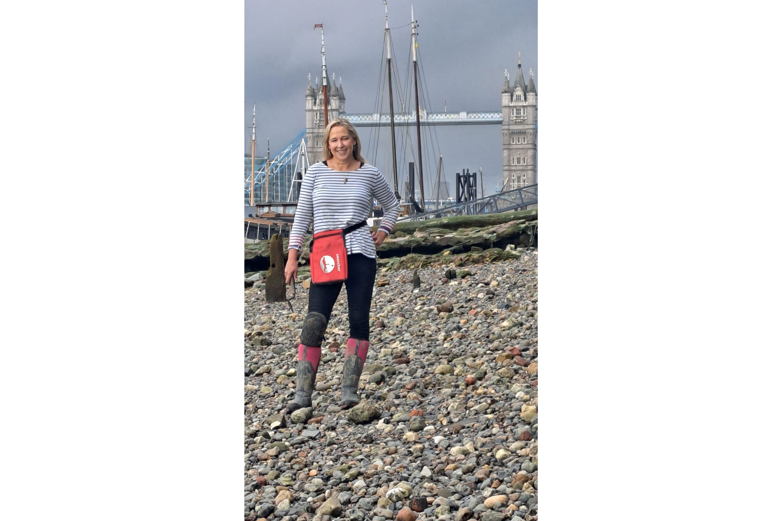 Nicola White stood on a pebble shore with Tower Bridge behind her