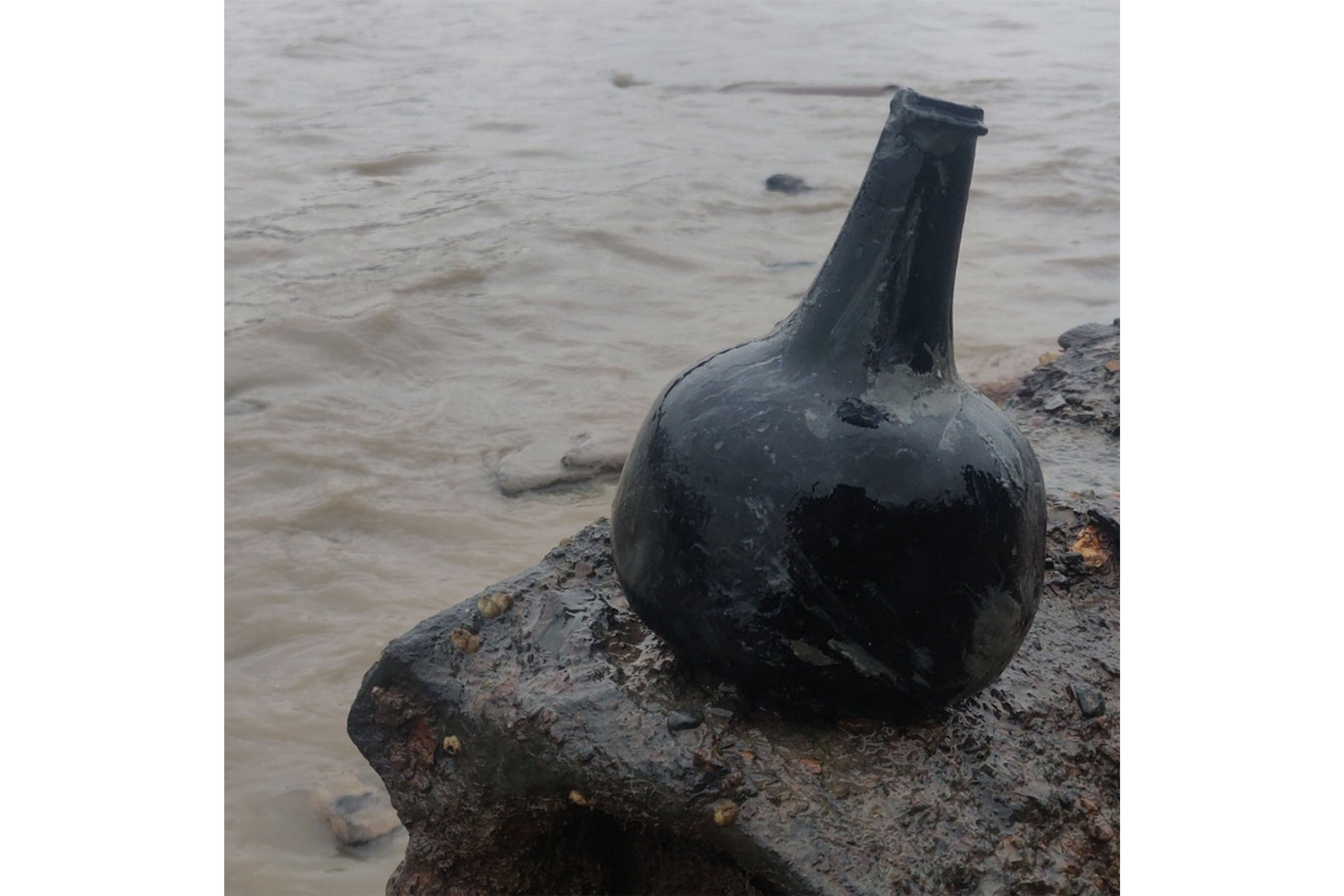 Die Flasche aus dem 18. Jahrhundert auf einem nassen Felsen