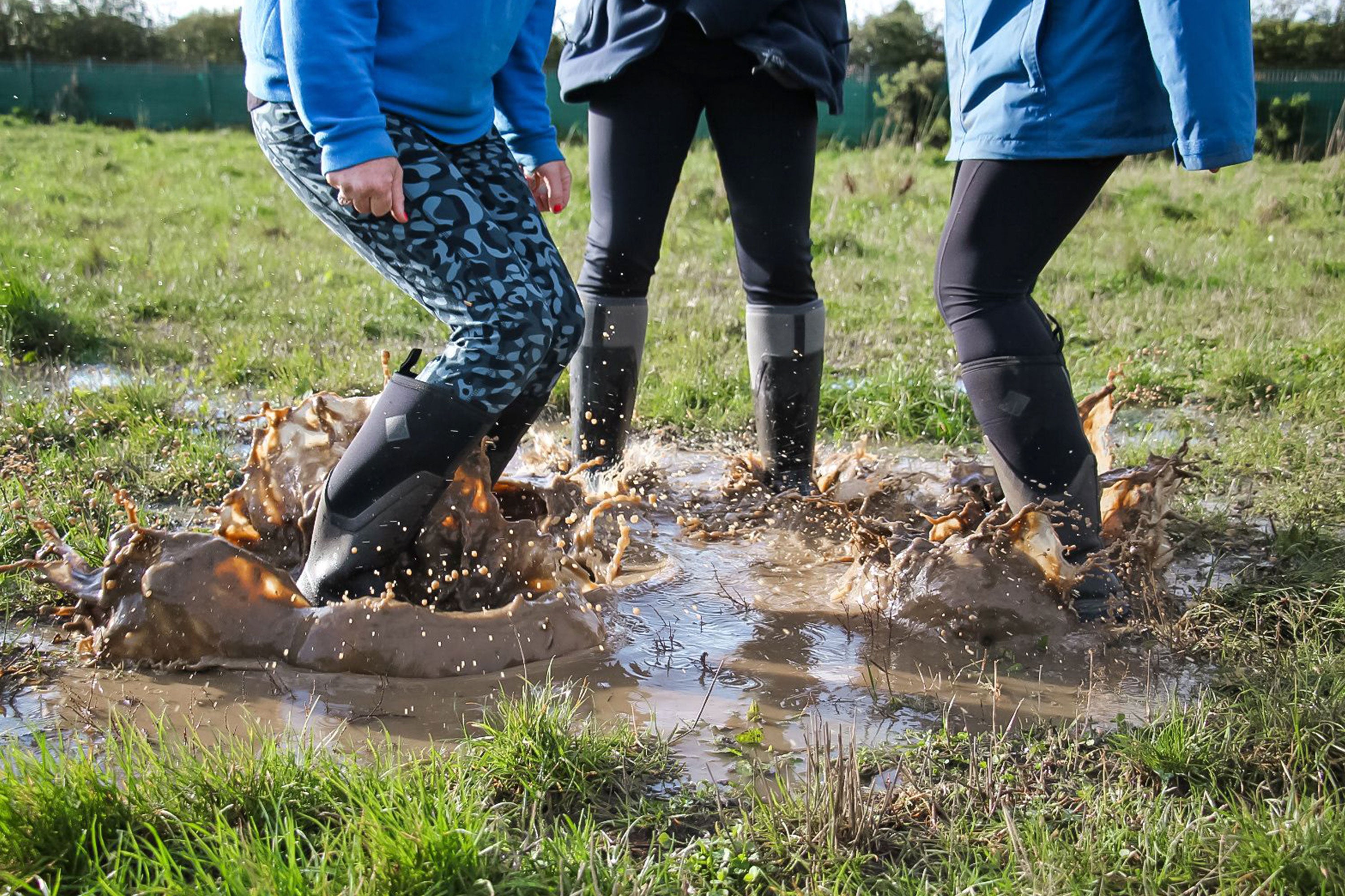 Bruce's Doggy Day Care team members jumping in a puddle, wearing pairs of Muck Boots