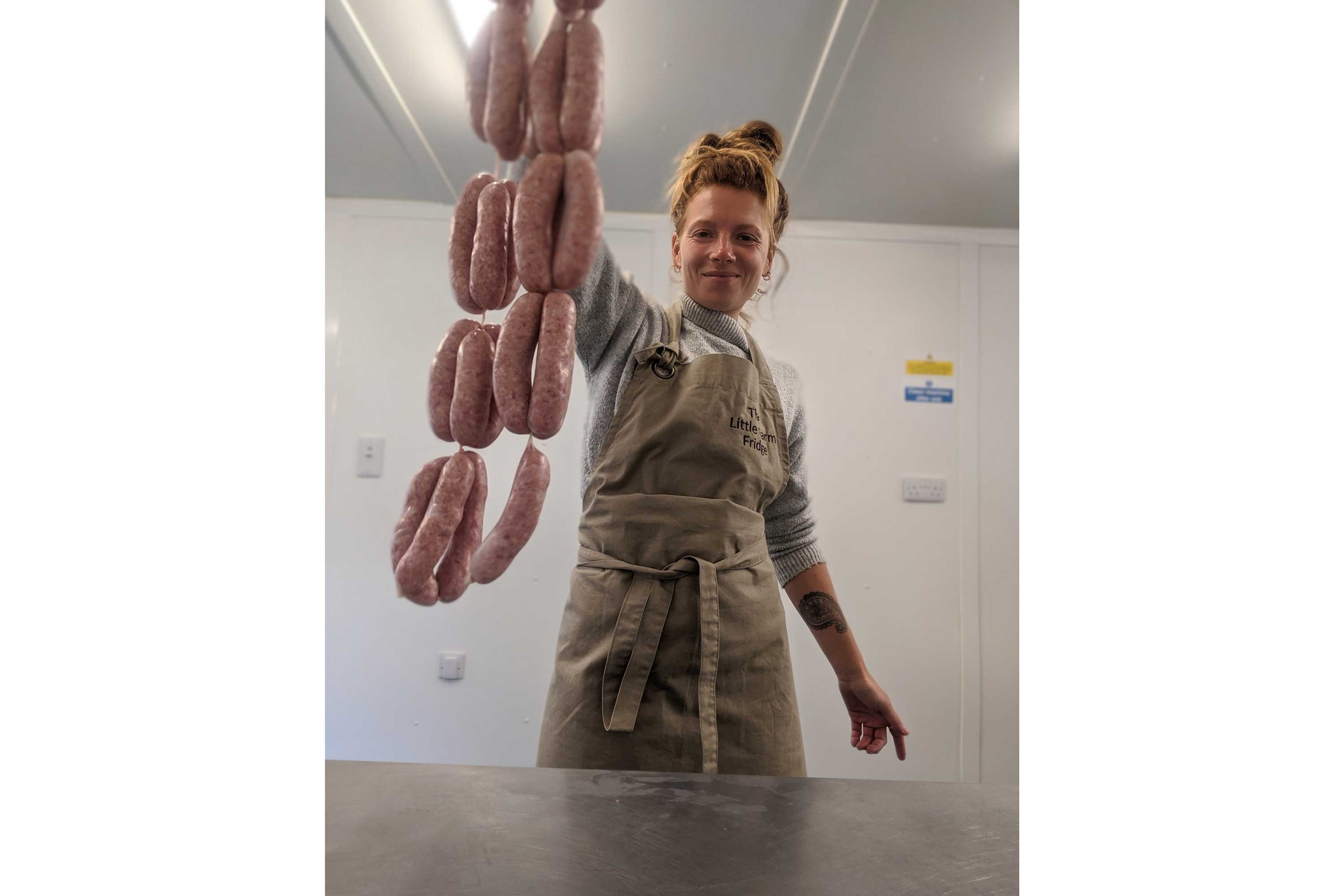 Zoe Colville wearing an apron and holding a string of sausages