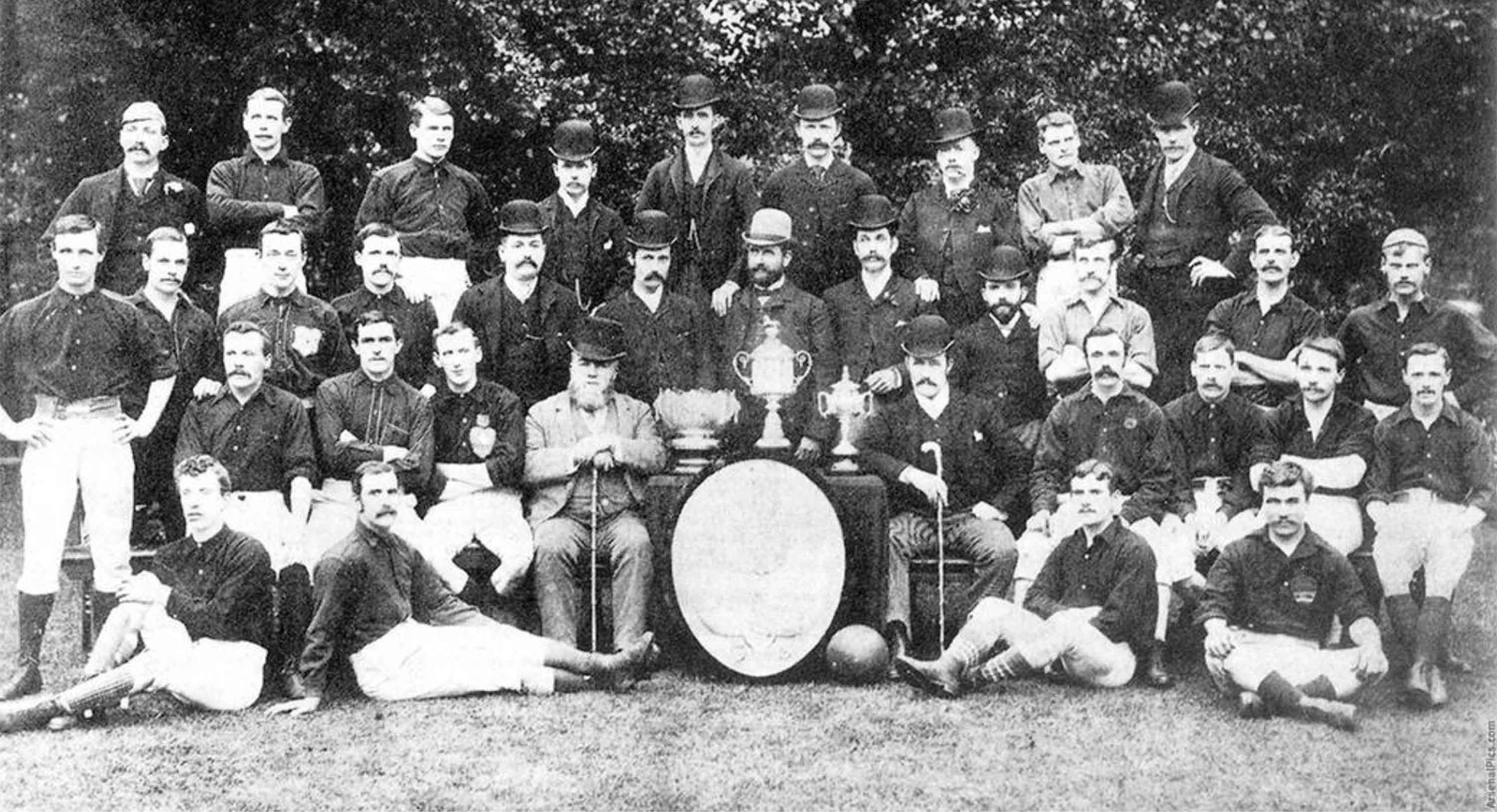 Black and White image of the late 19th Century Arsenal Football Club squad posing with trophies