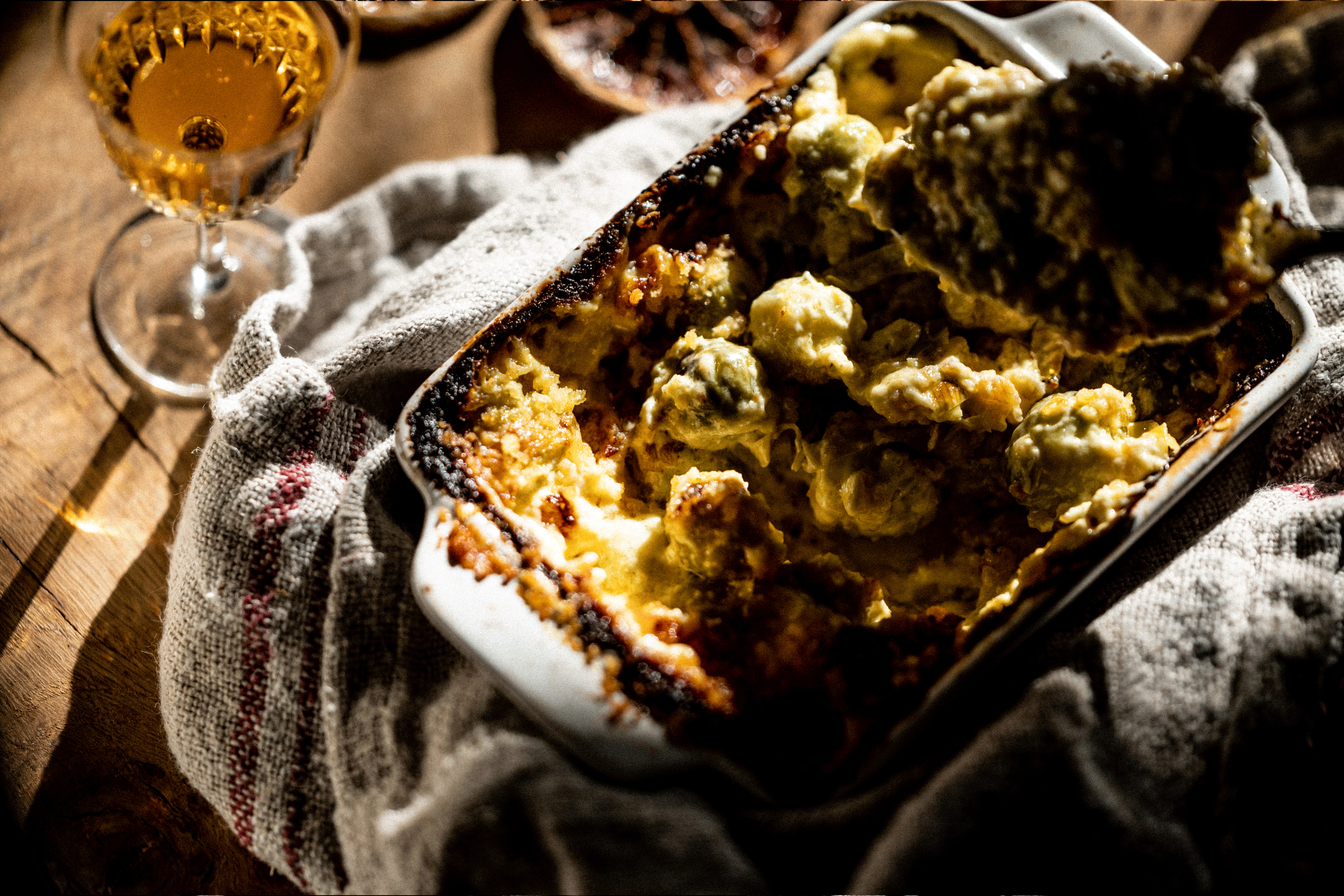 Cheesy roasted sprouts in a hot dish held with a dish cloth ready to be plated up.