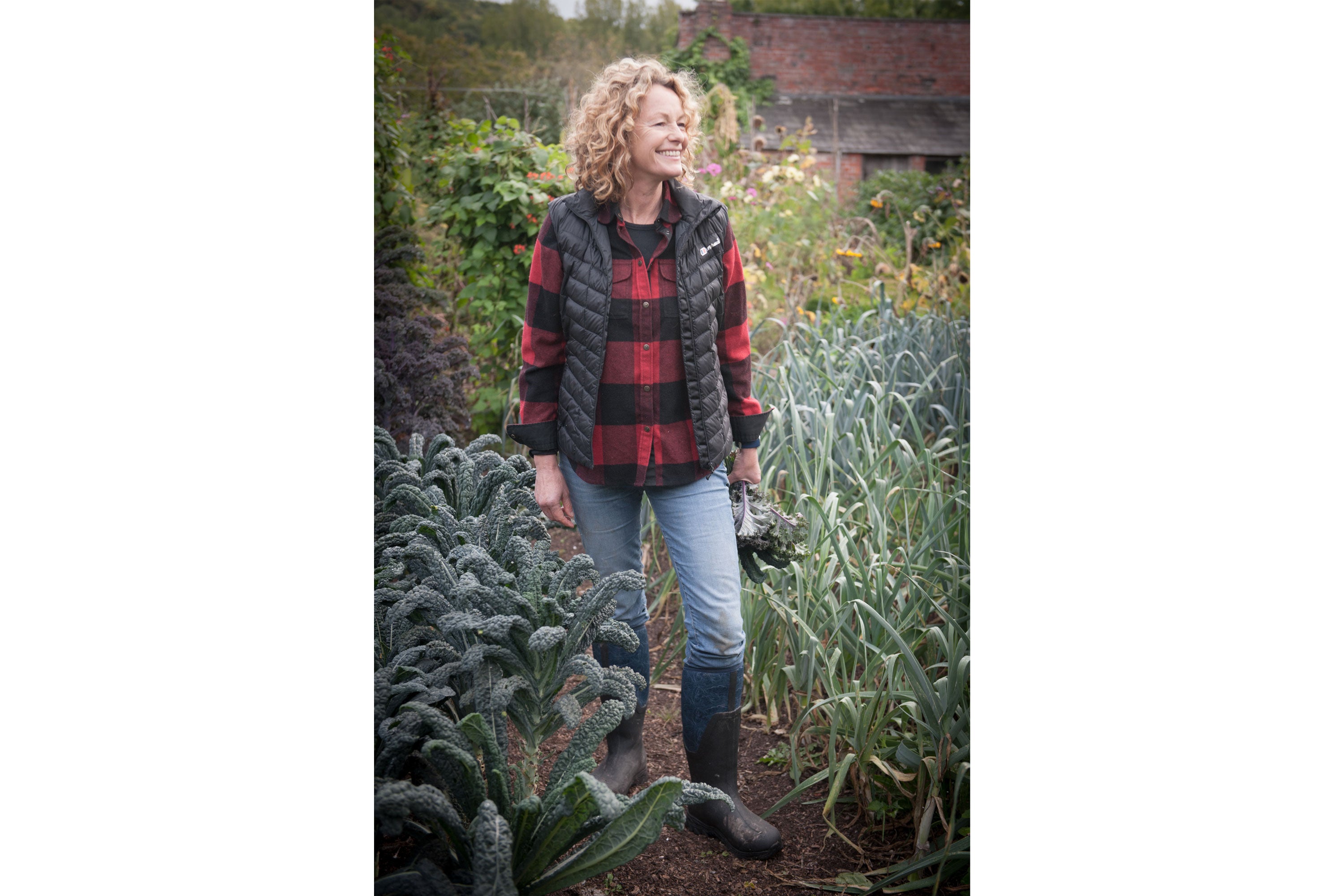 Kate Humble standing in a garden wearing a gilet