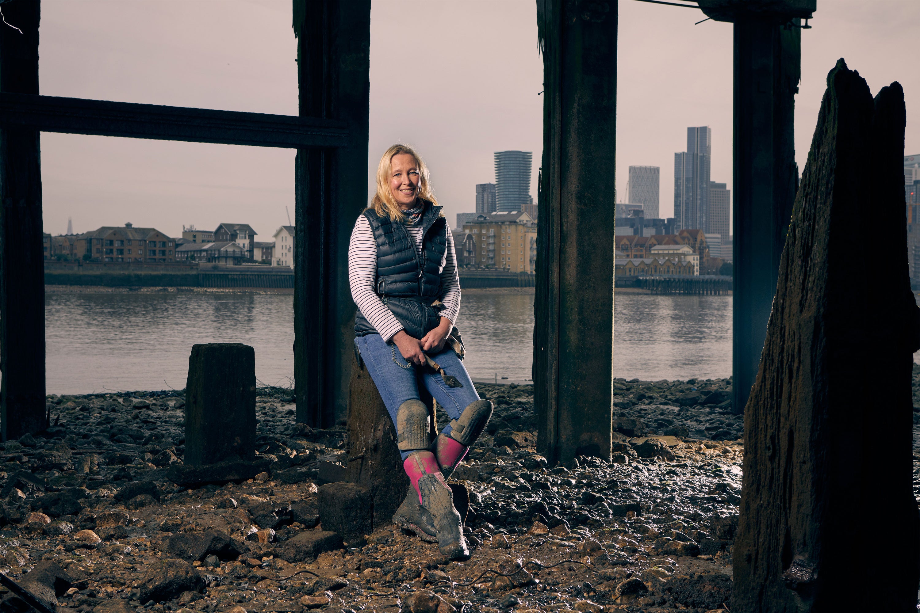 Nicola stood under a bridge with the Thames and London skyline behind her