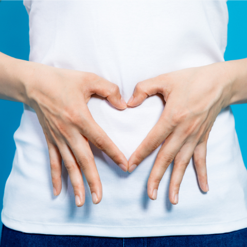 woman holding hands in heart over stomach