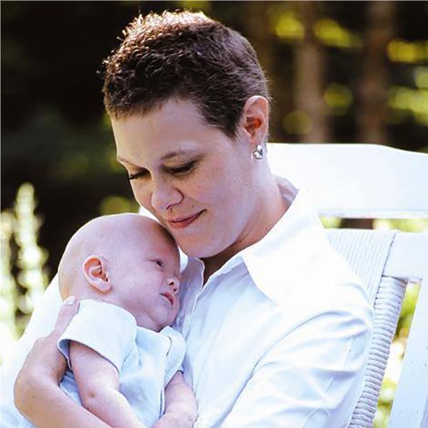 Heidi with regrown hair after chemotherapy holding a baby.