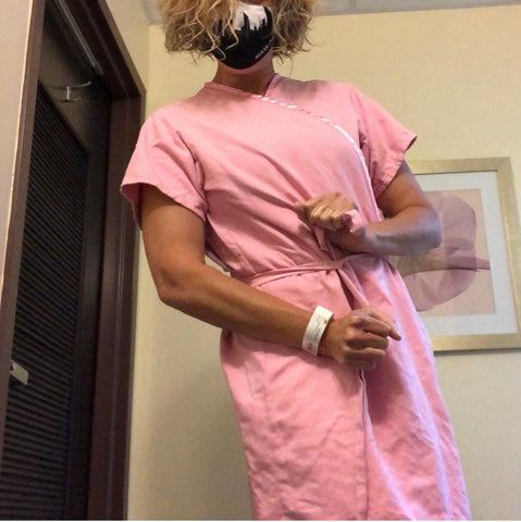 Heidi posing in a pink hospital gown during breast cancer treatment