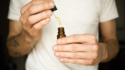 A man holding a small bottle of cbd oil.