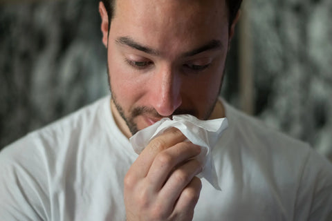 A man blowing his nose and having a cold.