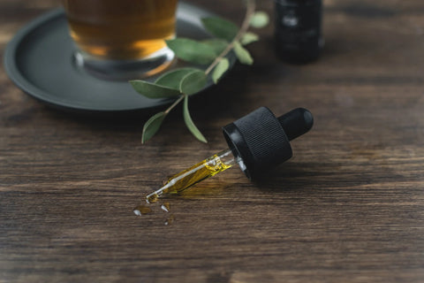 Small pipette with cbd oil in it, on a dark wooden table