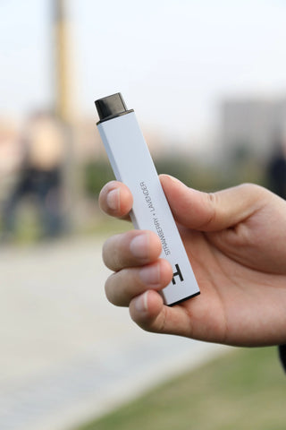 A person holding a vape in their hand.