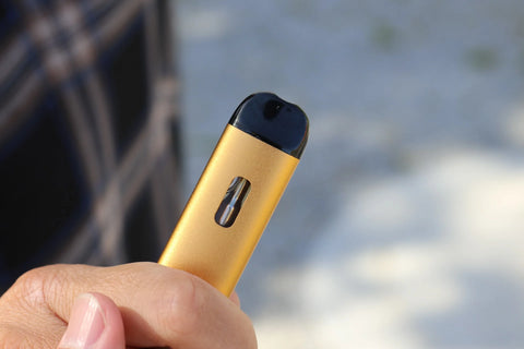 A person holding a yellow golden vape.