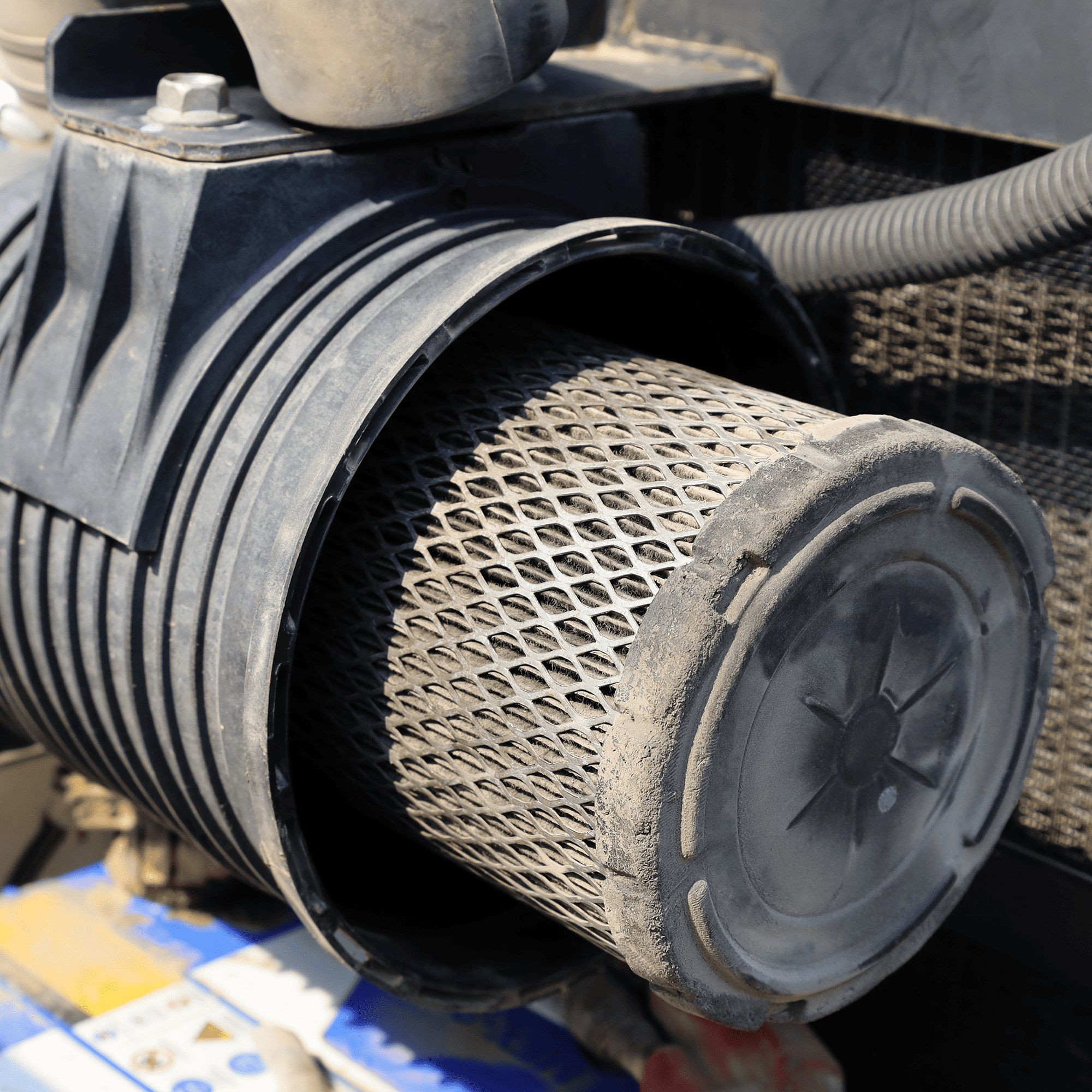 Close up of a dirty air filter in its housing in an engine bay