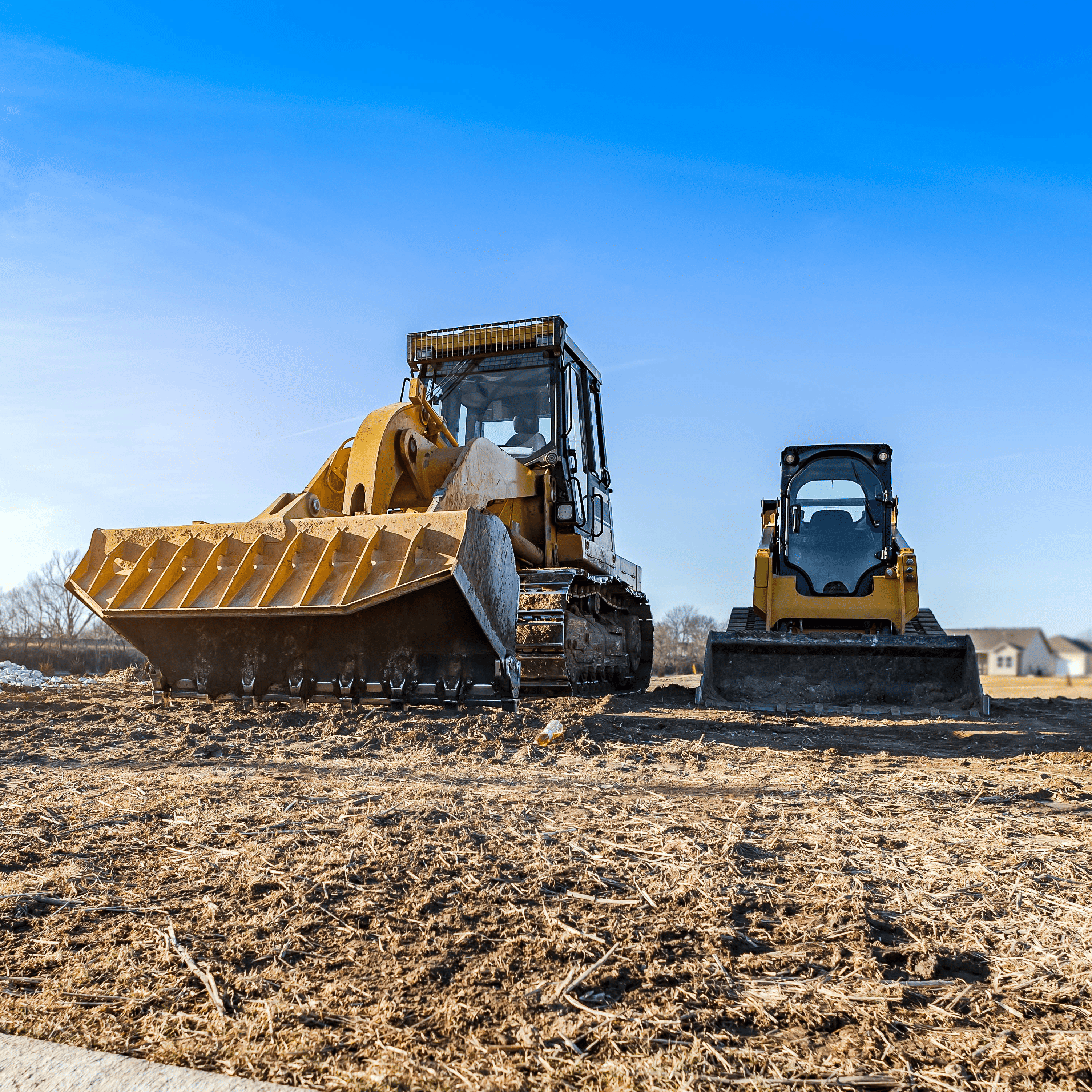 Two track loaders leveling out dirt