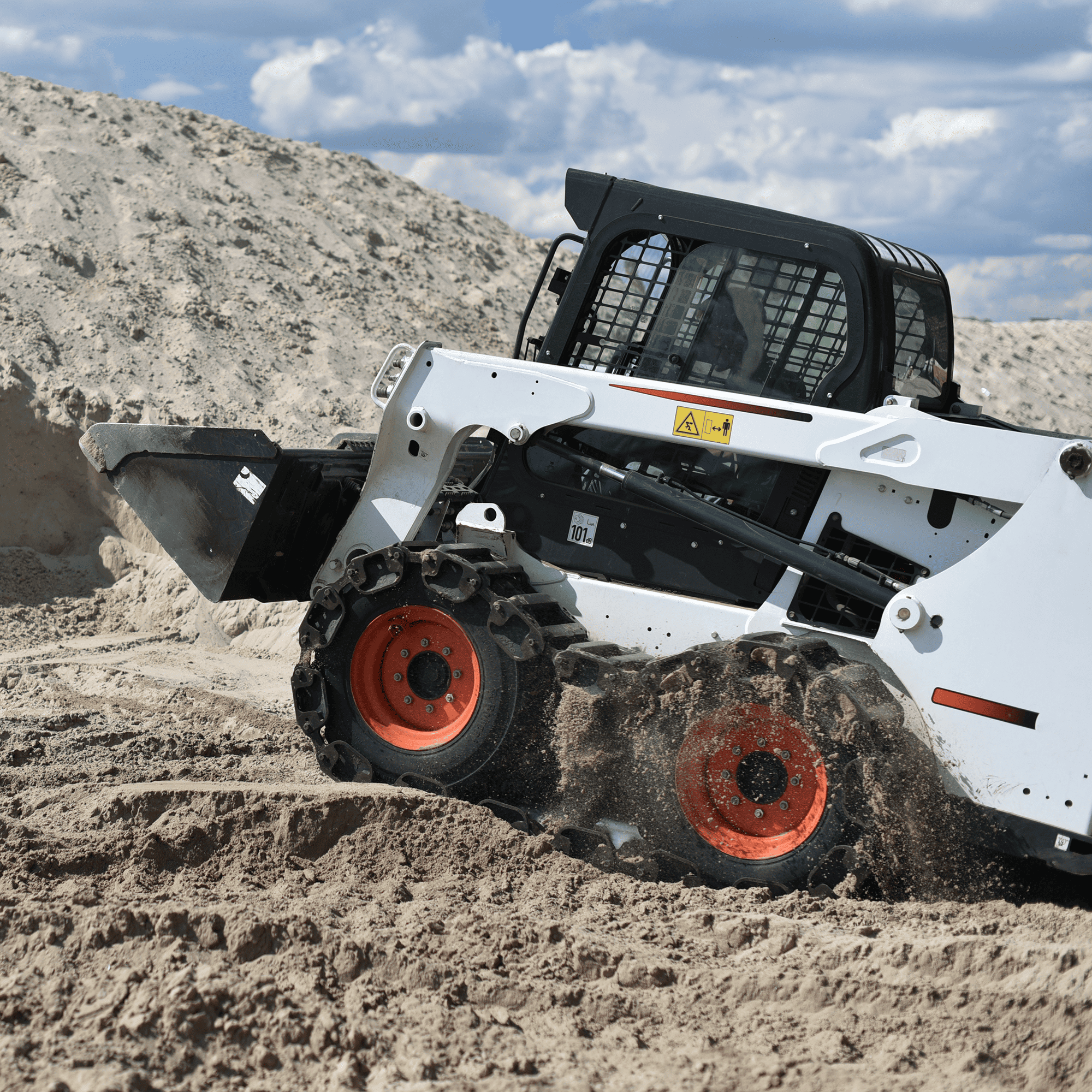 A skid steer moving up a hill of dirt 