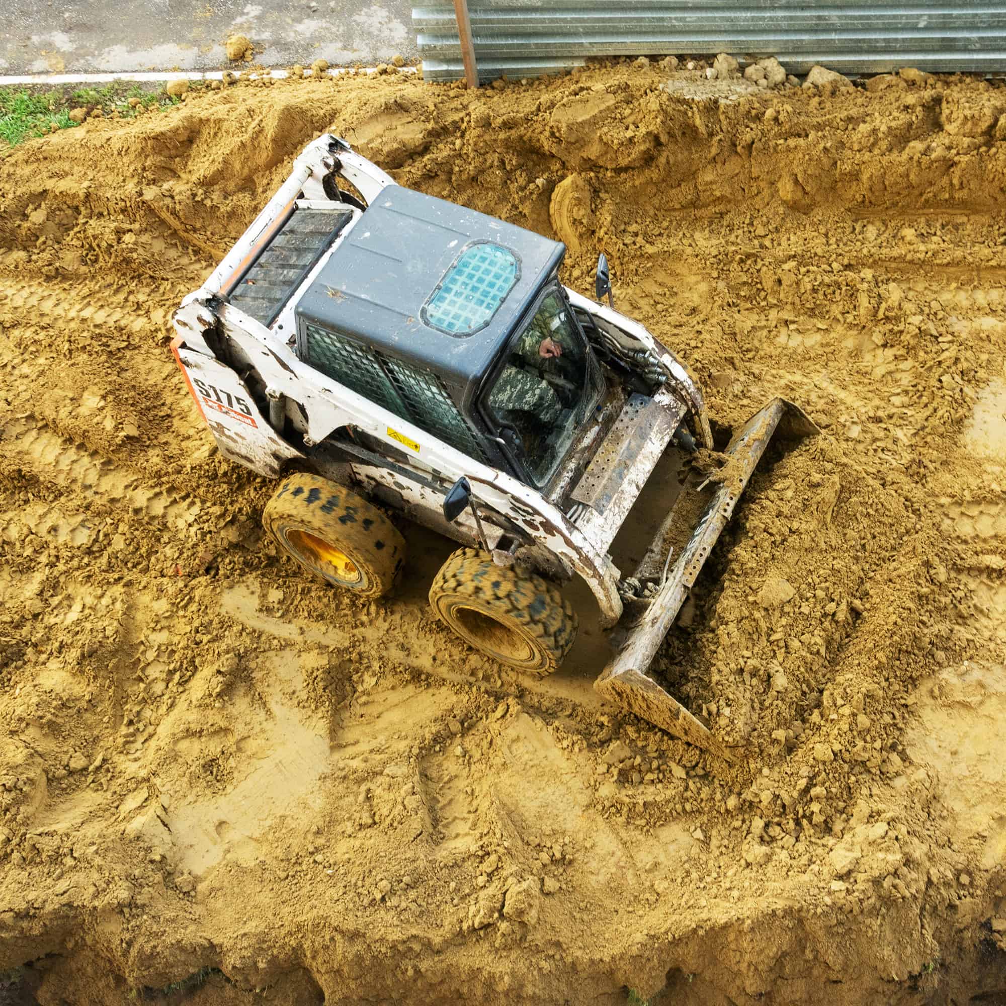 A skid steer moving dirt on a larger dirt plateau